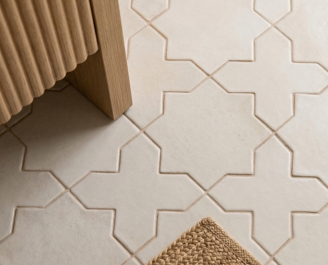 Pearl Snap Star & Cross tile by Clay Imports, a light geometric pattern on a floor with fluted wood and a woven mat.