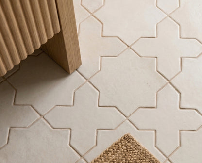Pearl Snap Star & Cross tile by Clay Imports, a light geometric pattern on a floor with fluted wood and a woven mat.