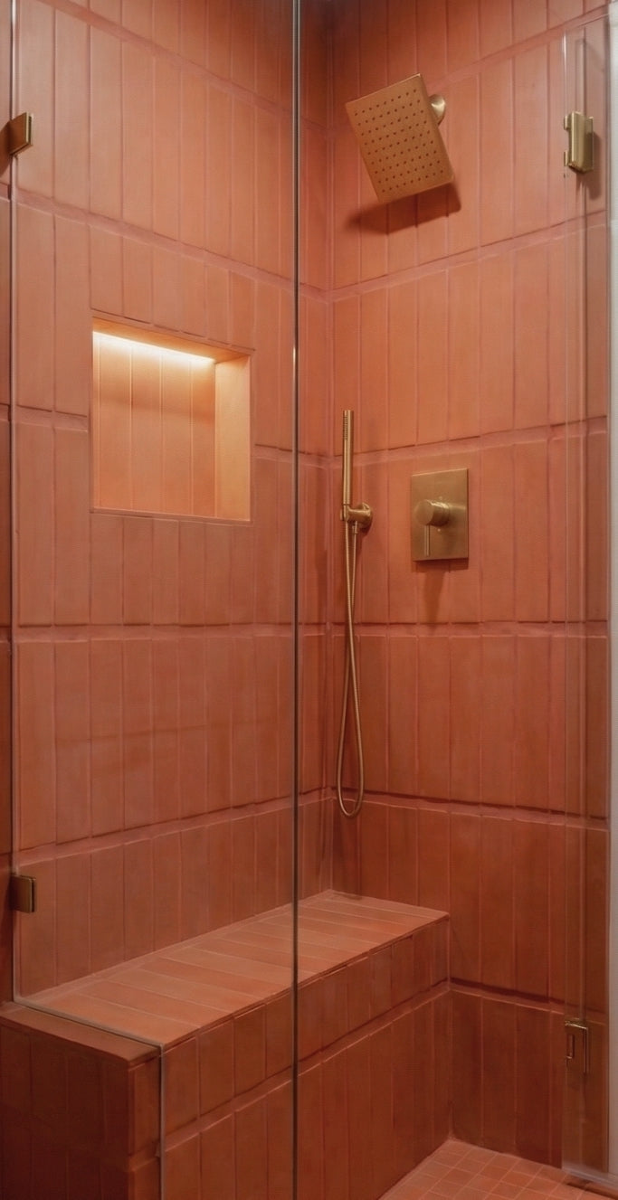 Terracotta solid tile by Clay Imports, vertically laid in a modern shower with a lit niche, bench, and brass fittings.