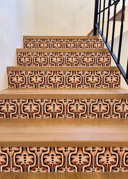 Wooden stairs with decorative patterned ceramic tiles wrapped around the risers, featuring a repeating geometric and floral motif in terracotta, beige, and black.