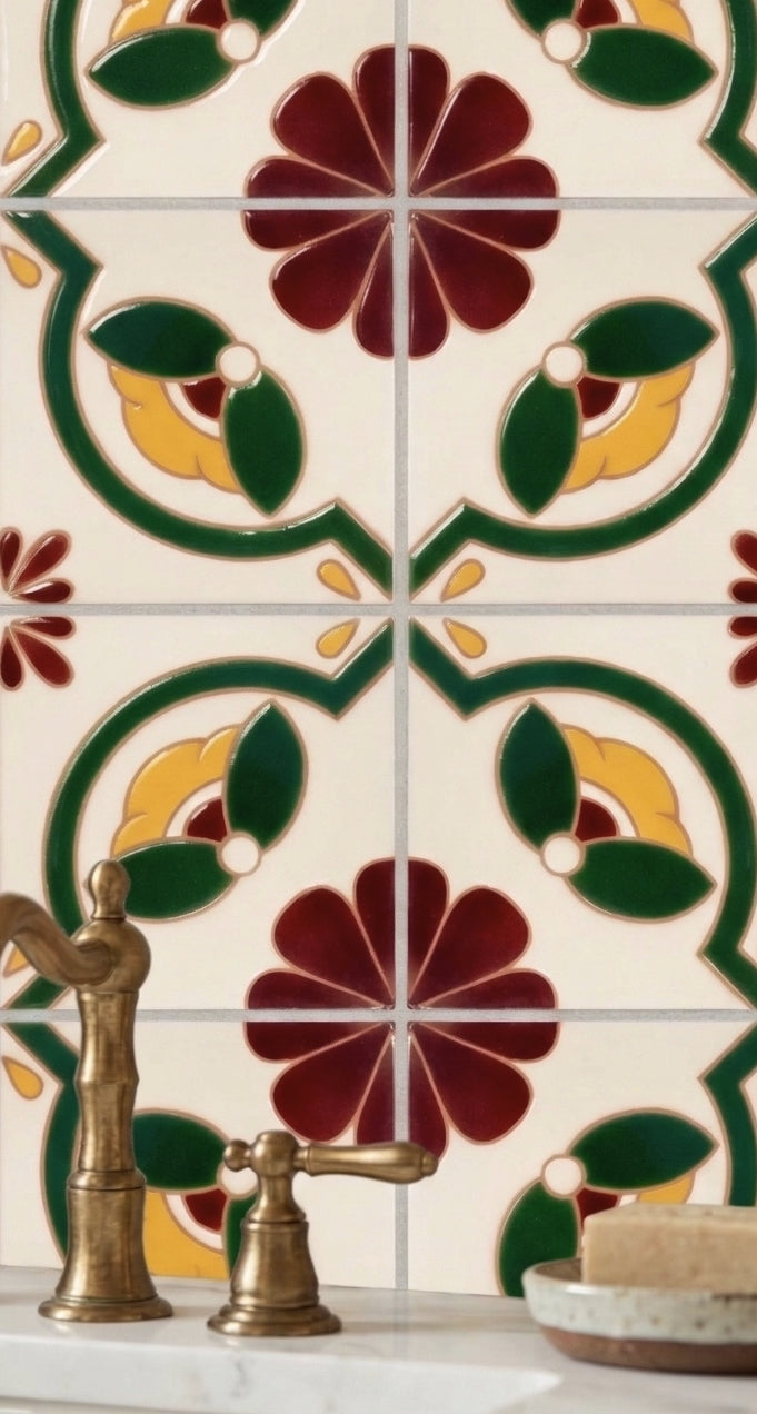 Relief Talavera tile from Clay Imports, featuring glossy raised floral and foliate patterns in red, yellow, and green, with a bronze faucet.