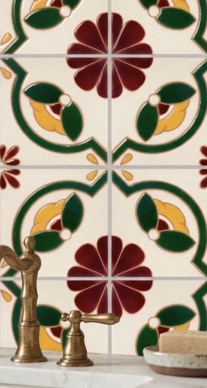 Relief Talavera tile from Clay Imports, featuring glossy raised floral and foliate patterns in red, yellow, and green, with a bronze faucet.