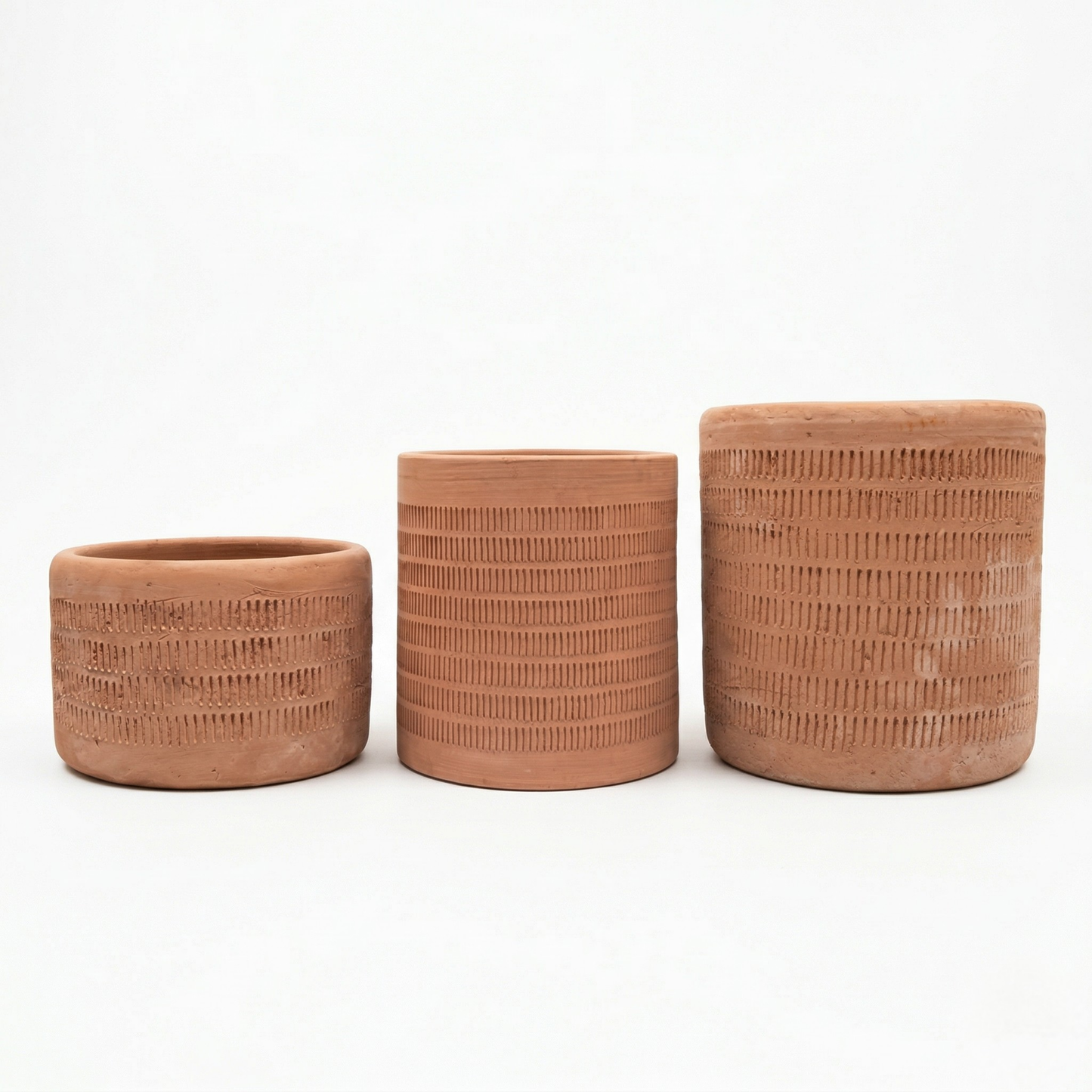 Three etched terracotta planters by Clay Imports in varying sizes with vertical stripe patterns on a white background.