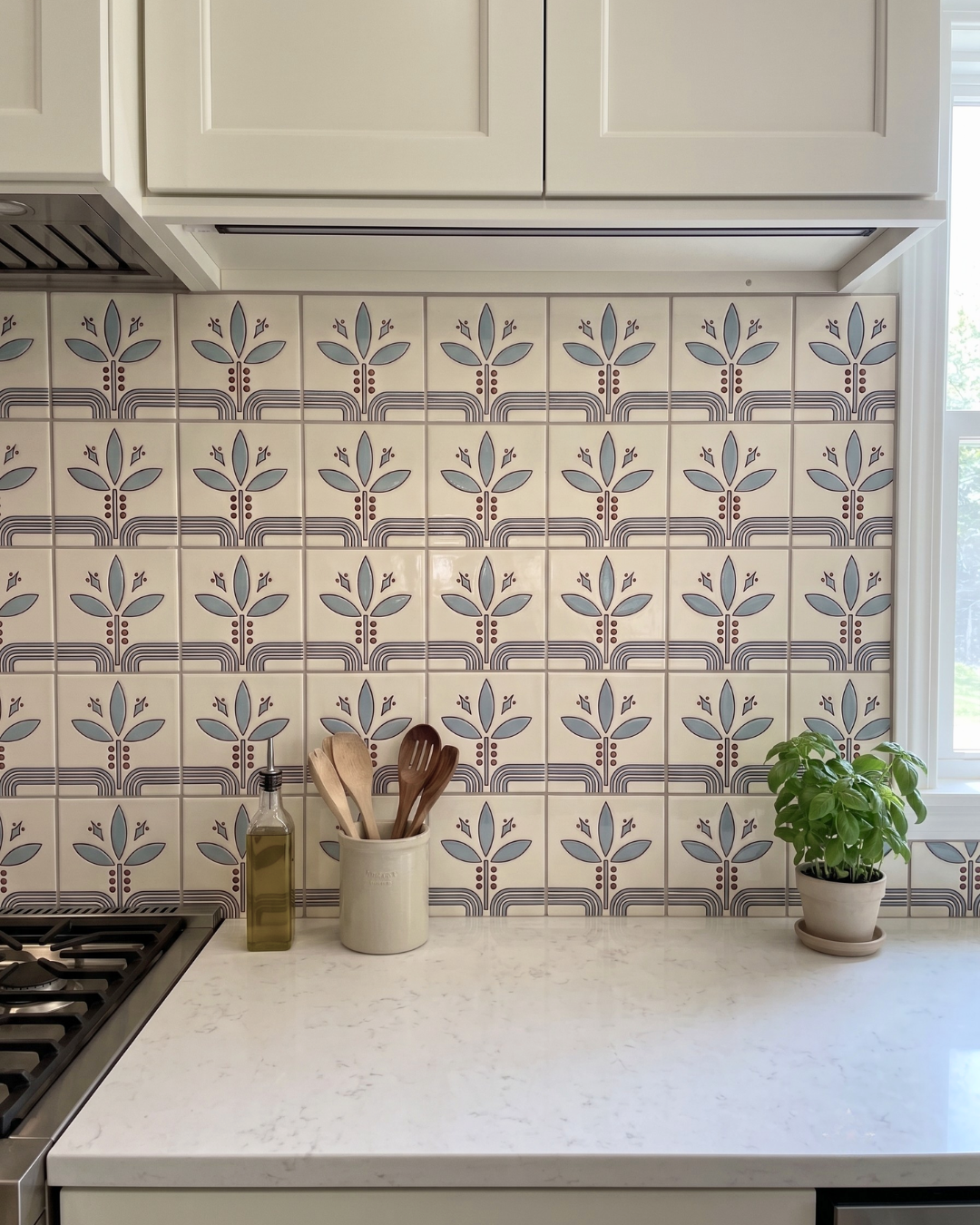 Kitchen with patterned tile backsplash, white cabinets, and a countertop with kitchen items.