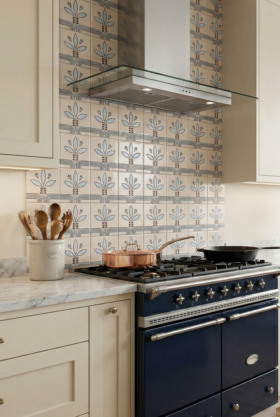 Cream relief pattern tile by Clay Imports with repeating stylized blue leaf motifs and geometric lines on a kitchen backsplash.