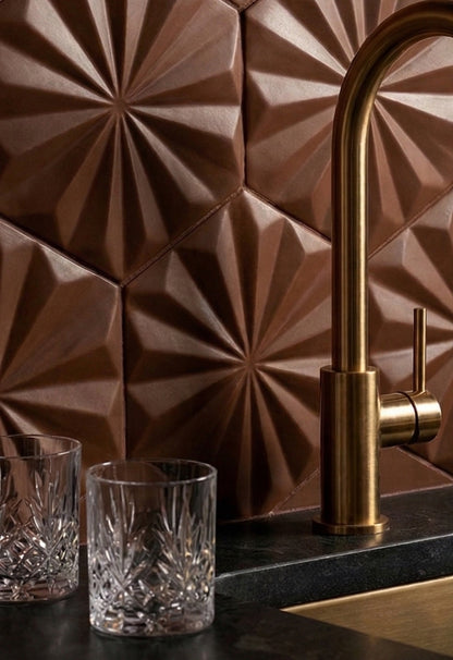 Brown hexagonal solid tile by Clay Imports with a raised geometric starburst pattern, used as a kitchen backsplash.