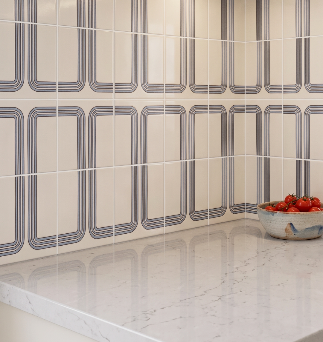 Tiled wall with geometric pattern and a bowl of tomatoes on a marble countertop.
