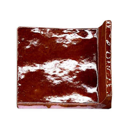 Root beer brown glossy cove base tile trim by Clay Imports, showing a smooth, curved corner.