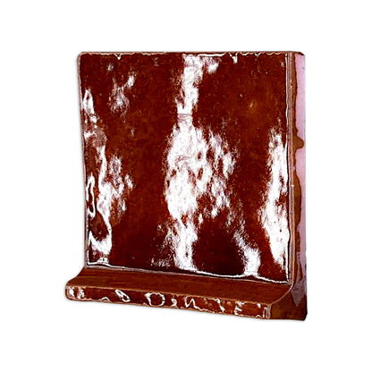 Root beer brown 6x6 cove base tile trim by Clay Imports with a glossy, textured surface, shown at an angle.