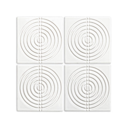 White glossy 6x6 tiles by Clay Imports with a raised pattern of concentric circles bisected by a vertical segmented line.