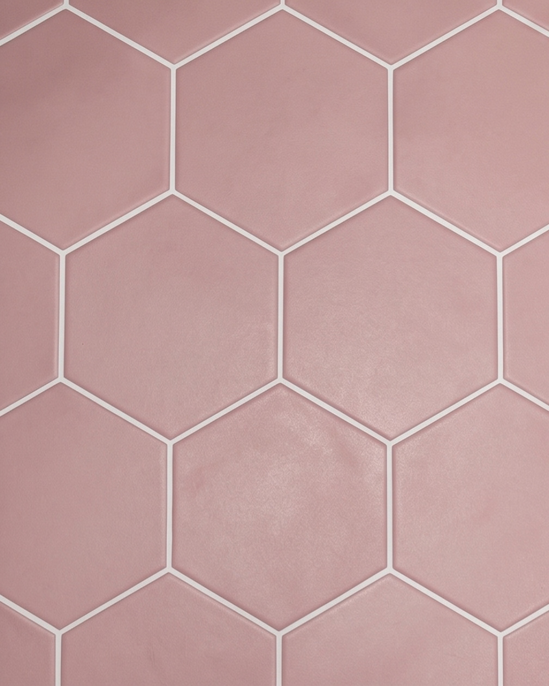 Matte pink hexagonal ceramic tiles with contrasting white grout create a modern geometric backsplash.