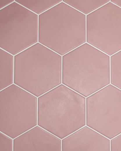 Matte pink hexagonal ceramic tiles with contrasting white grout create a modern geometric backsplash.