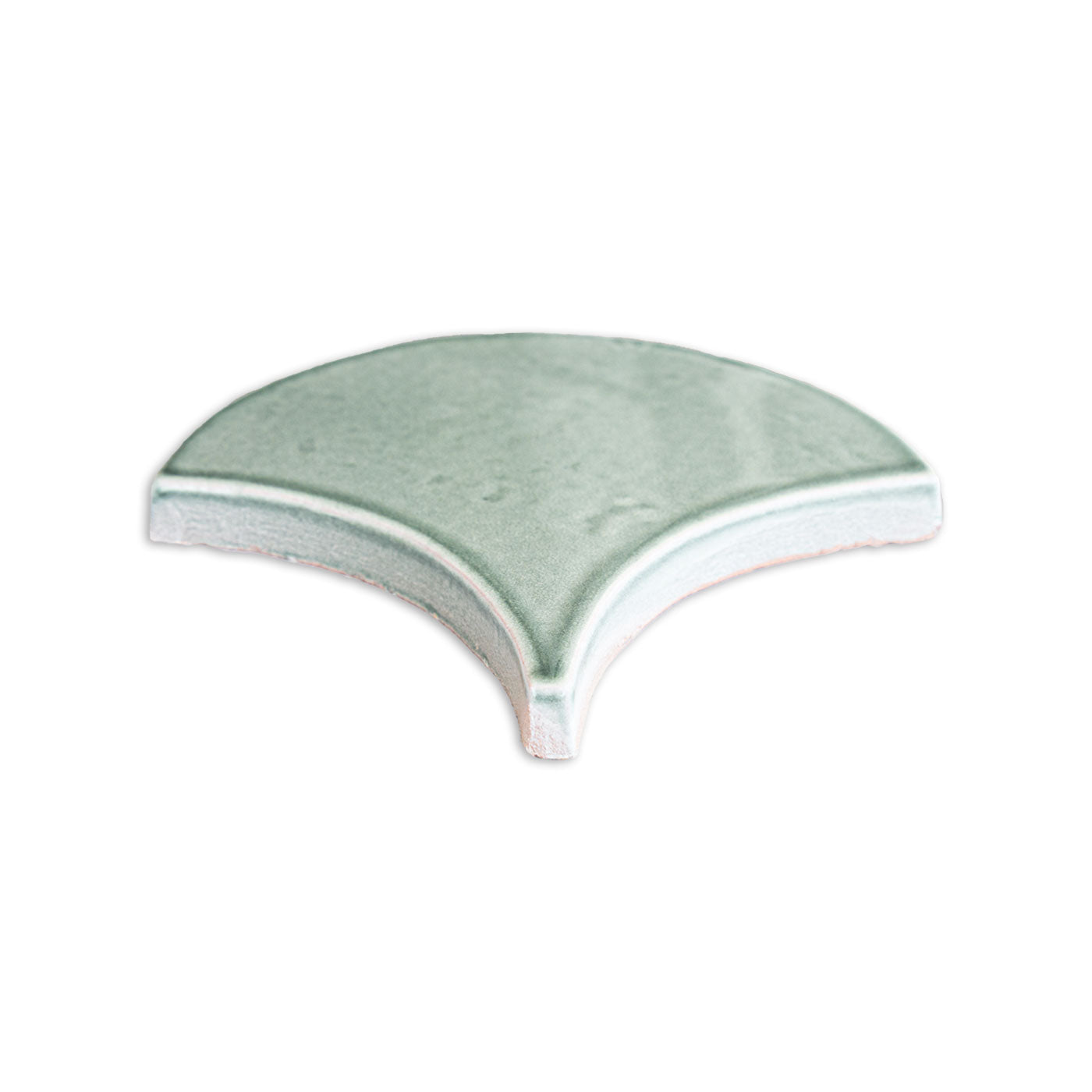 Arctic gloss fan-shaped tile by Clay Imports, featuring a light green hue and exposed terracotta edges.