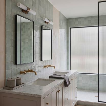 Light blue glossy 6x6 ceramic tile by Clay Imports in modern bathroom with marble vanity and black-framed mirrors