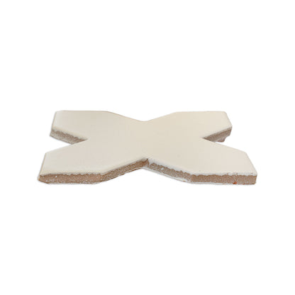 A vanilla cross solid tile by Clay Imports, viewed from an elevated angle, showing a textured surface and natural unglazed sides.