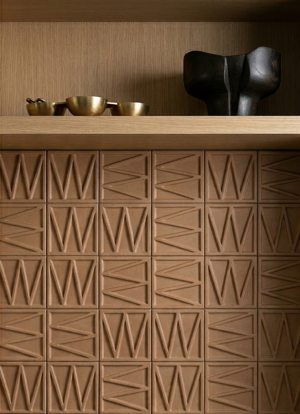 Terracotta solid tile by Clay Imports with an angular geometric relief pattern, installed below a wooden shelf.
