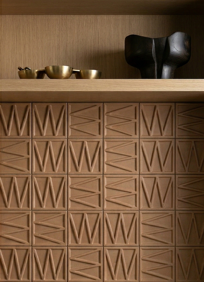 Terracotta solid tile by Clay Imports with an angular geometric relief pattern, installed below a wooden shelf.