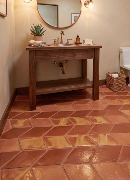 Terracotta herringbone floor tiles in a rustic bathroom setting with a wooden vanity, brass faucet, and warm beige walls.