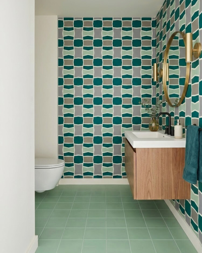 Maguey geometric clay tile by Clay Imports featuring teal, mint, gray, and brown shapes on a bathroom wall.