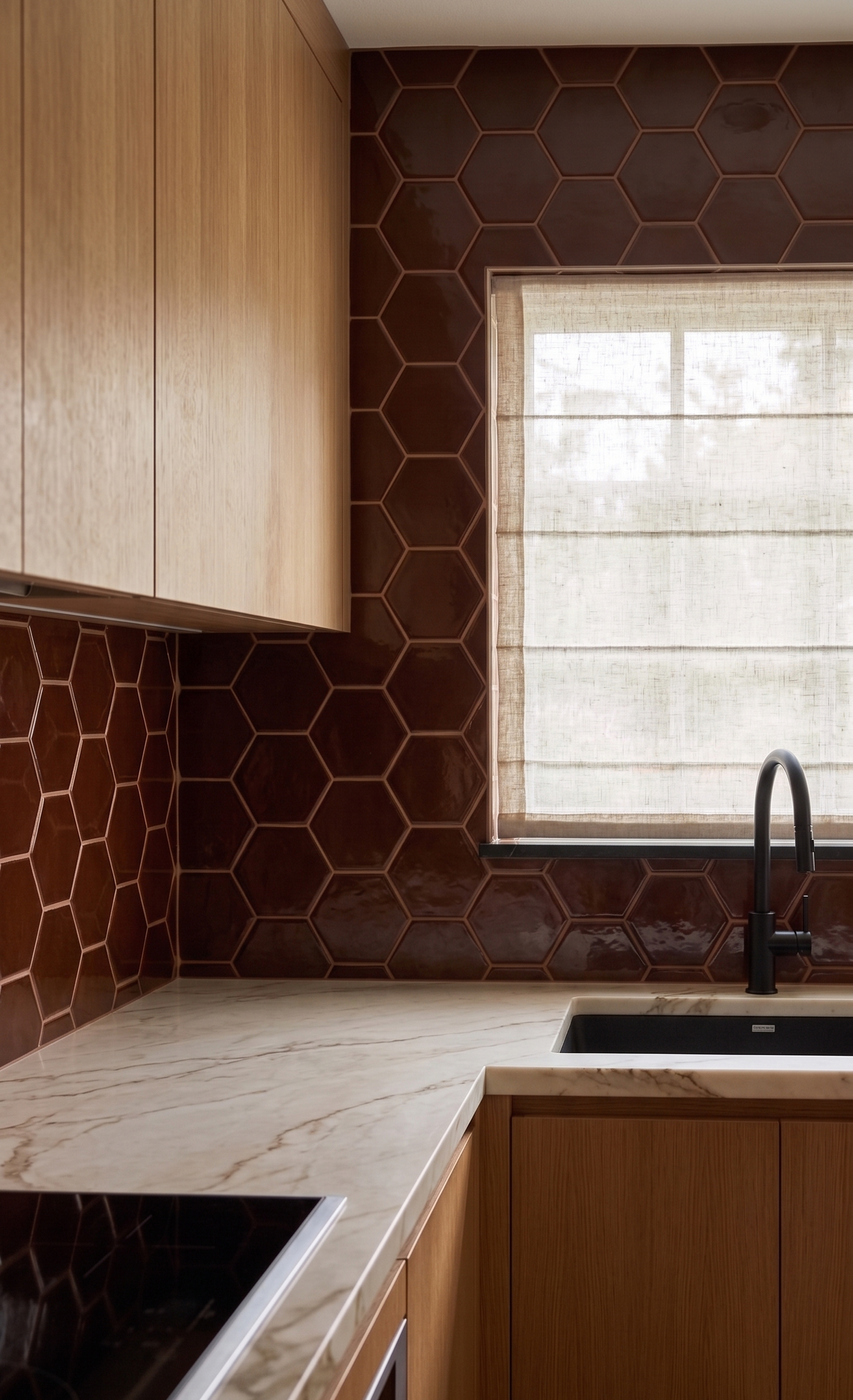 Hexagonal oxblood clay tiles by Clay Imports, featuring a glossy finish as a kitchen backsplash with marble countertop and wood cabinets.