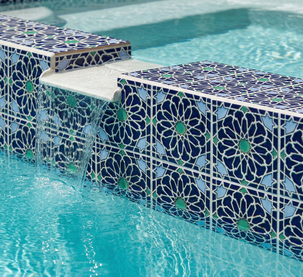 Deep blue Layla pattern tiles in a pool waterline, featuring geometric designs in blues and greens with cascading water.