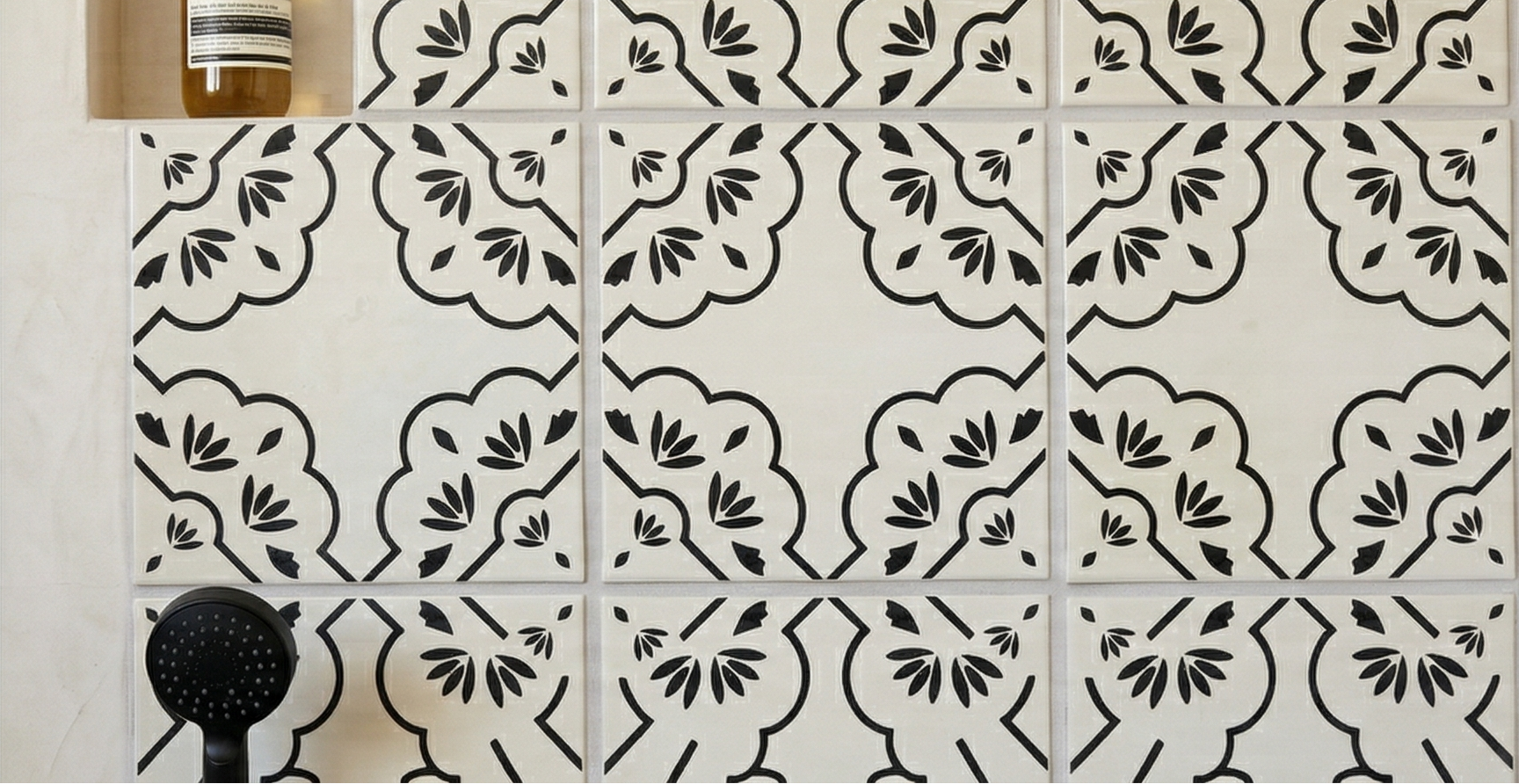 White Anejo Urbano hand-painted tiles by Clay Imports with black curvilinear patterns and leaf motifs.