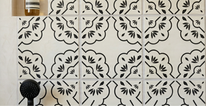 White Anejo Urbano hand-painted tiles by Clay Imports with black curvilinear patterns and leaf motifs.