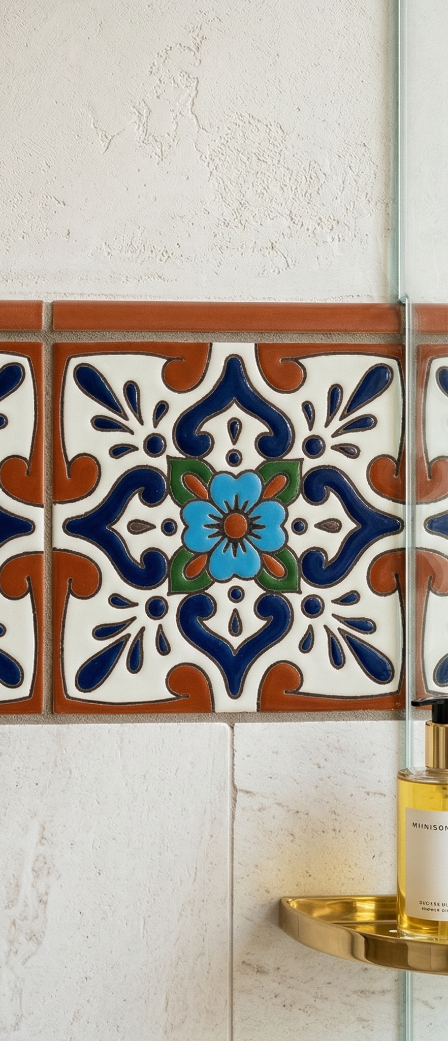 White Relief Talavera tile by Clay Imports featuring a blue floral pattern and dark blue scrollwork, set into a wall next to a glass shower.