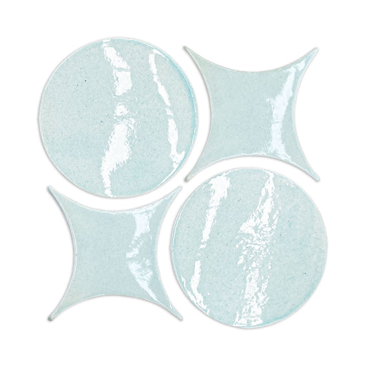 Light blue crackle-glazed ceramic plates and star-shaped tiles by Rombo & Circle, featuring glossy texture and geometric forms, arranged in overhead view.