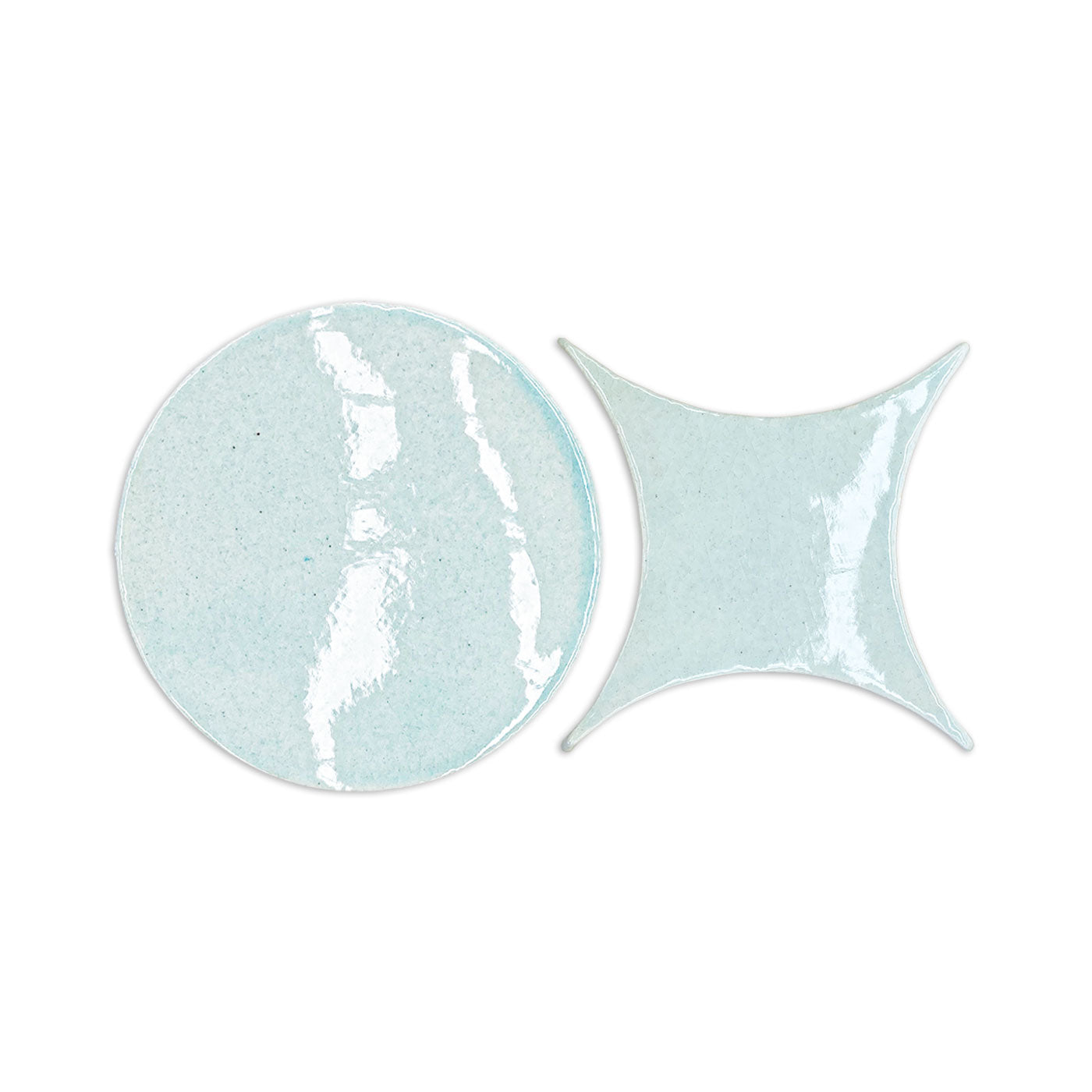 Light blue crackle-glazed ceramic coasters, one round and one diamond-shaped, by Rombo & Circle, with glossy textured finish, side view.