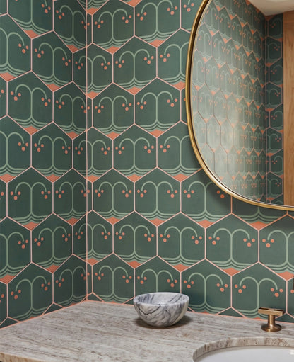 A round gold-rimmed mirror hangs above a marble vanity featuring patterned green hexagon tiles and a small marble bowl.