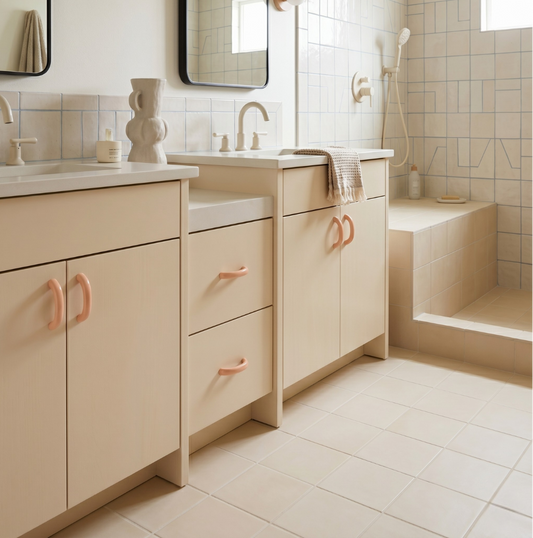 Beige bathroom vanity with pink handles in a tiled bathroom setting.