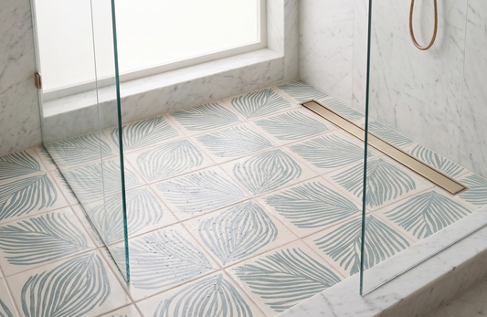 Cream pattern tile by Clay Imports with light blue palm leaf pattern in a shower with a linear drain.