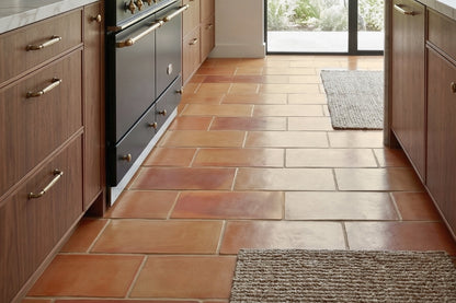 Supremo Rounded terracotta tiles by Clay Imports in varied warm reddish-brown and orange tones, rectangular with rounded edges, on a kitchen floor.
