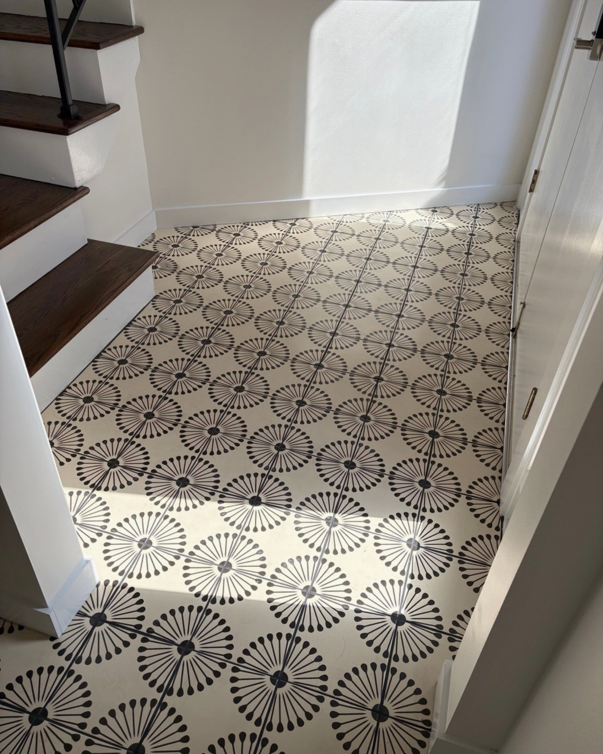 Pitch black atomic burst pattern tile by Vocho, 8x8 inch, cream background with bold black radial motifs, installed in entryway floor, lifestyle view