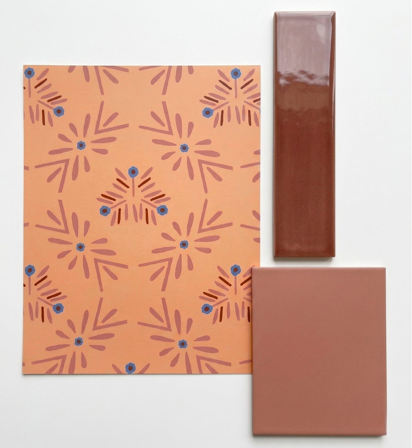 Orange patterned Adobe Bloom sample by Clay Imports, displaying abstract floral motifs, alongside glossy brown and matte terracotta tiles.