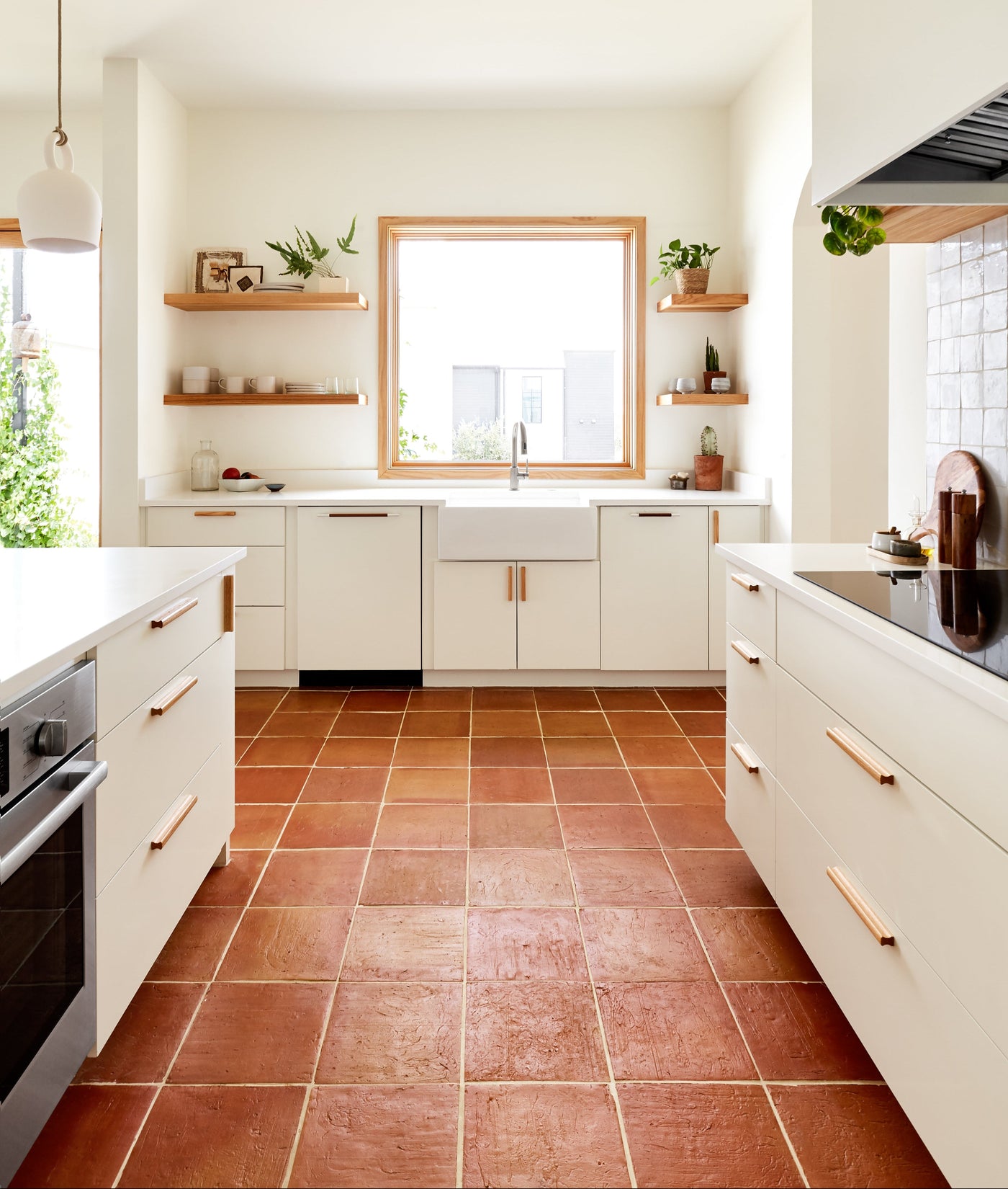 Antique Satin 12x12 terracotta tiles by Clay Imports, in a rustic reddish-brown with light grout lines on a kitchen floor.