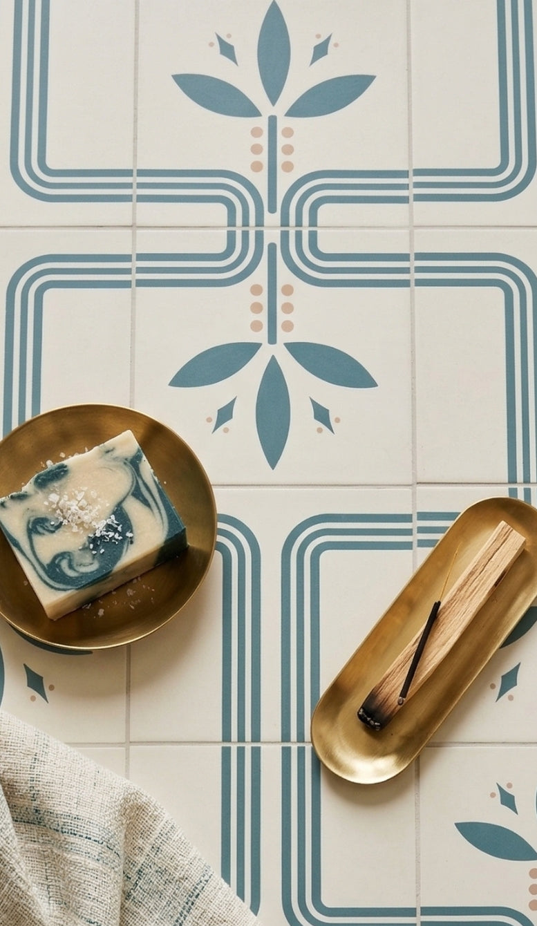 Bayas Vocho White 8x8 pattern tile by Clay Imports, displaying blue geometric and floral designs with pink dots, with soap and incense.