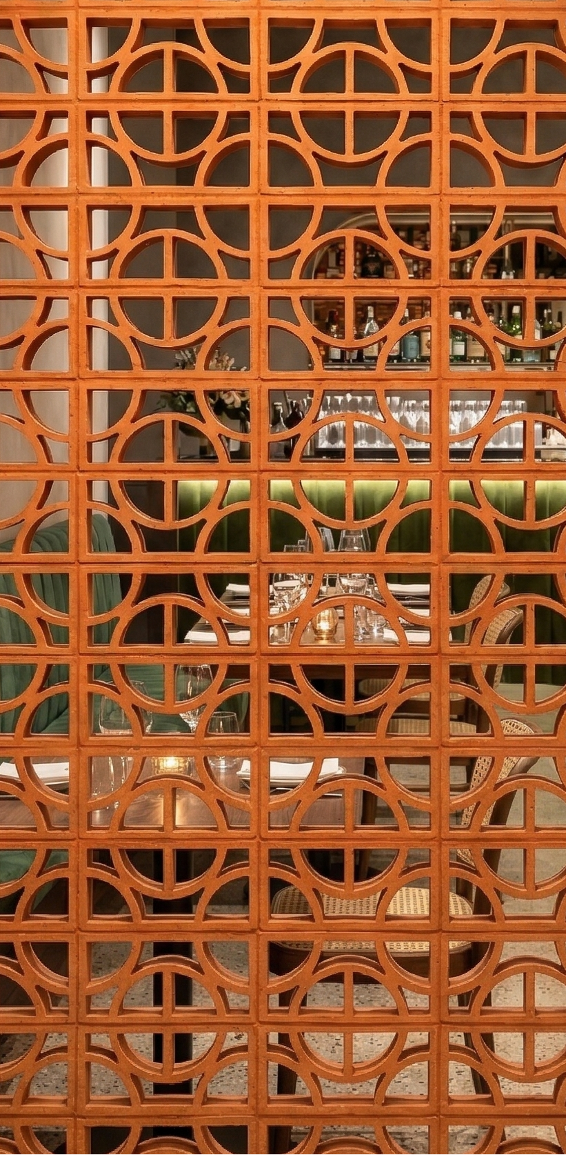 Terracotta Disco Breeze Block by Clay Imports Breeze Blocks, an intricately patterned divider in a restaurant.