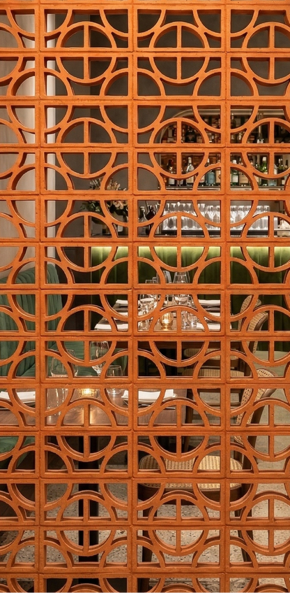 Terracotta Disco Breeze Block by Clay Imports Breeze Blocks, an intricately patterned divider in a restaurant.