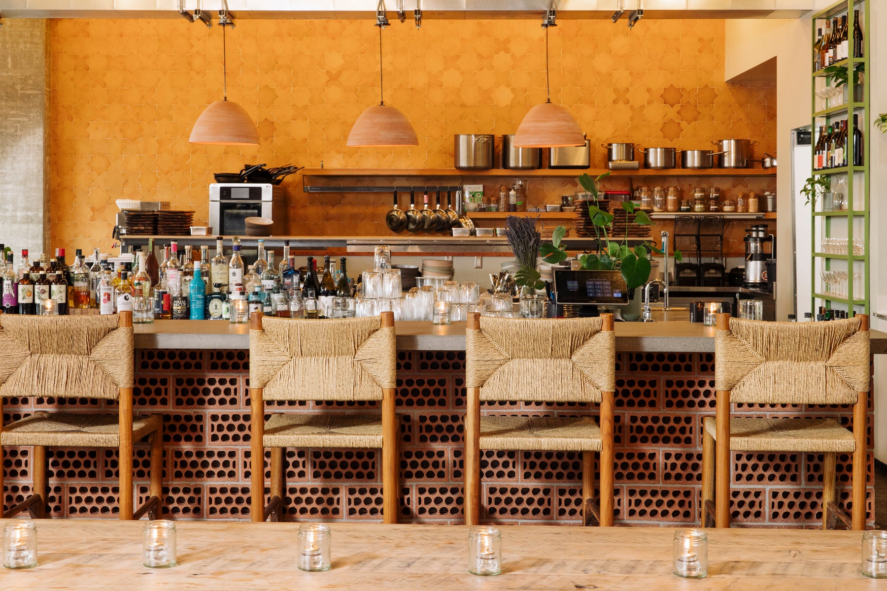 Terracotta Breeze Blocks with Pozos pattern by Clay Imports Breeze Blocks, forming a decorative wall behind woven bar stools.