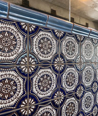 Glossy blue ceramic chair rail tile by Clay Imports, featuring a curved profile and installed above decorative patterned tiles.