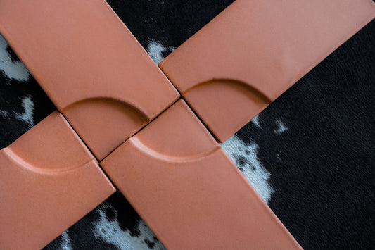 Terracotta-colored clay tile by Clay Imports with a quarter-circle curve design, arranged on a black and white cowhide rug.