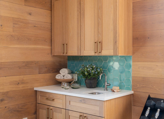 Kitchen with wooden cabinets, white countertop, and aqua blue hexagonal tile backsplash.