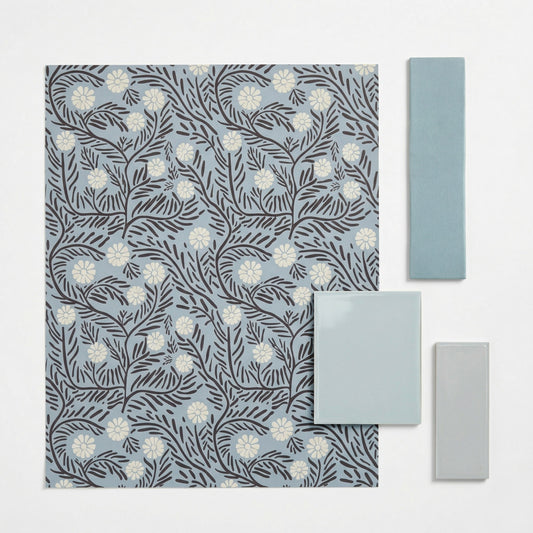 Light blue patterned tile by Clay Imports, featuring dark brown floral motifs and white daisy-like flowers, displayed with solid teal and light grey rectangular tiles.