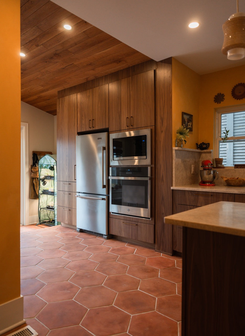 Modern kitchen with wooden cabinets, stainless steel appliances, and cotto  terracotta hexagonal floor tiles.