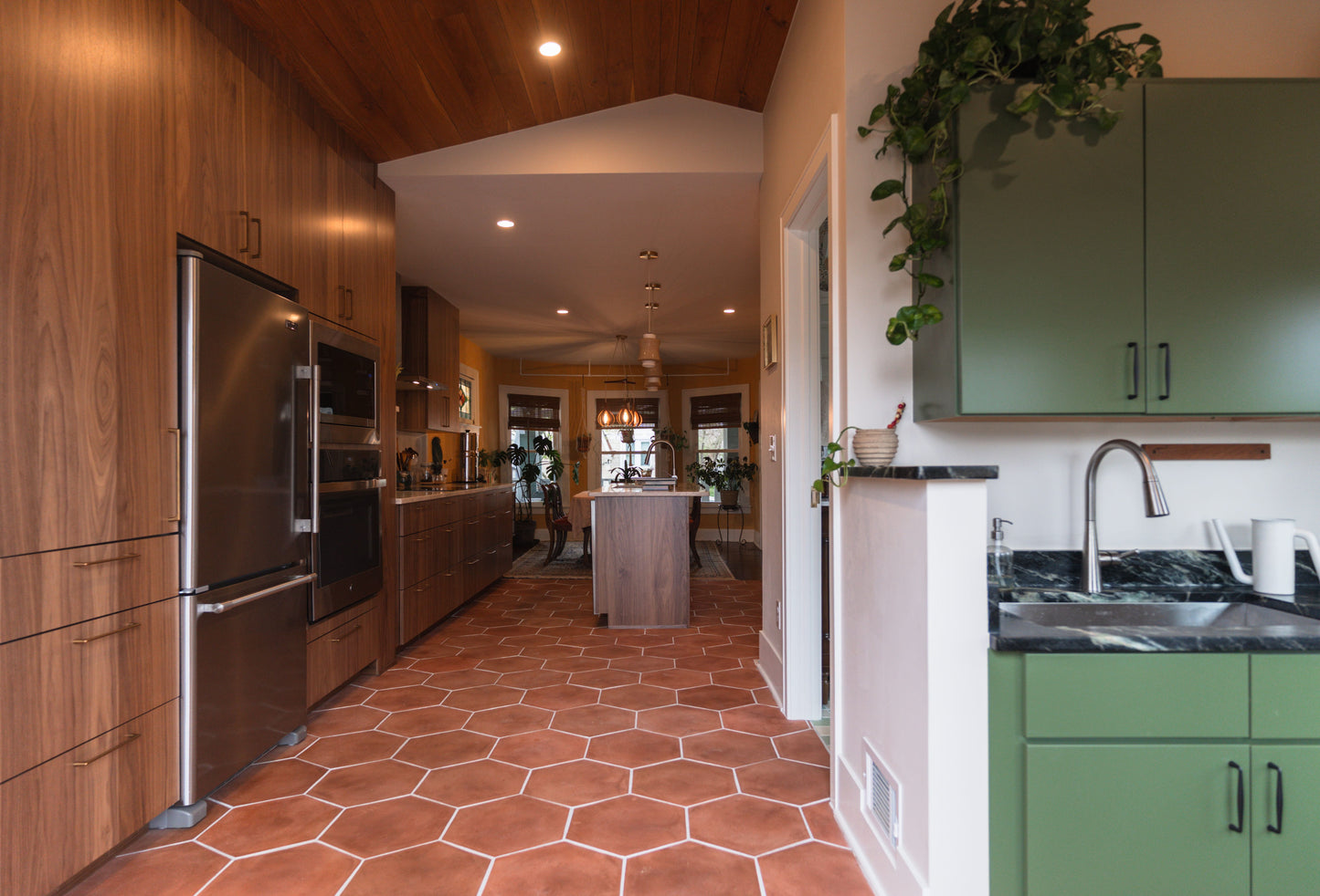 Modern kitchen with wooden cabinets, stainless steel appliances, and hexagonal cotto terracotta floor tiles.