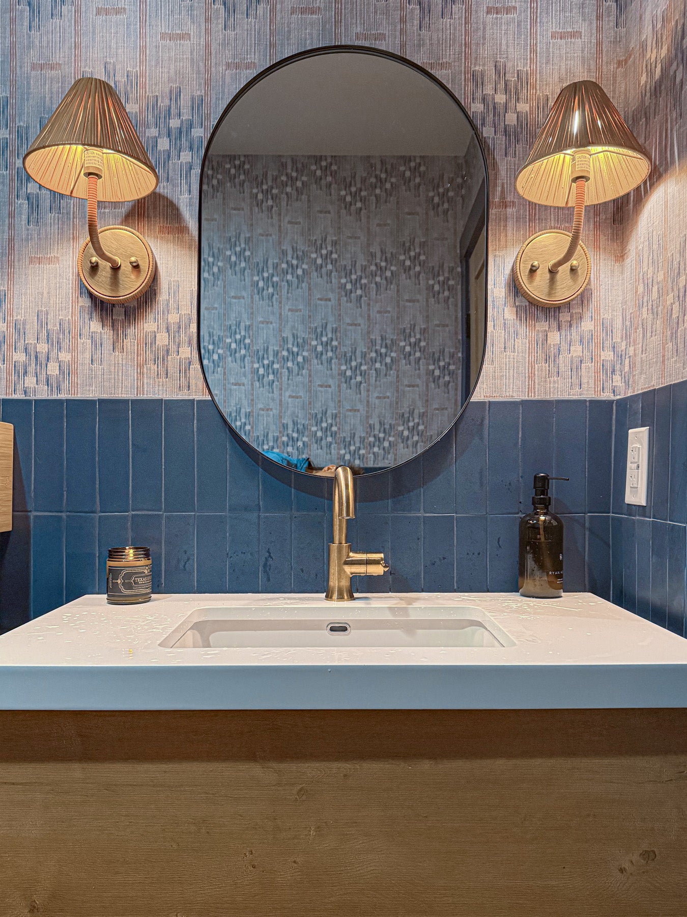 Midnight blue clay subway tiles by Clay Imports, accenting a white vanity with gold faucet and oval mirror.