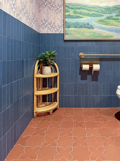 Vertical midnight blue 2x8 clay tiles by Clay Imports on a bathroom wall, contrasting with patterned wallpaper and terracotta floor.