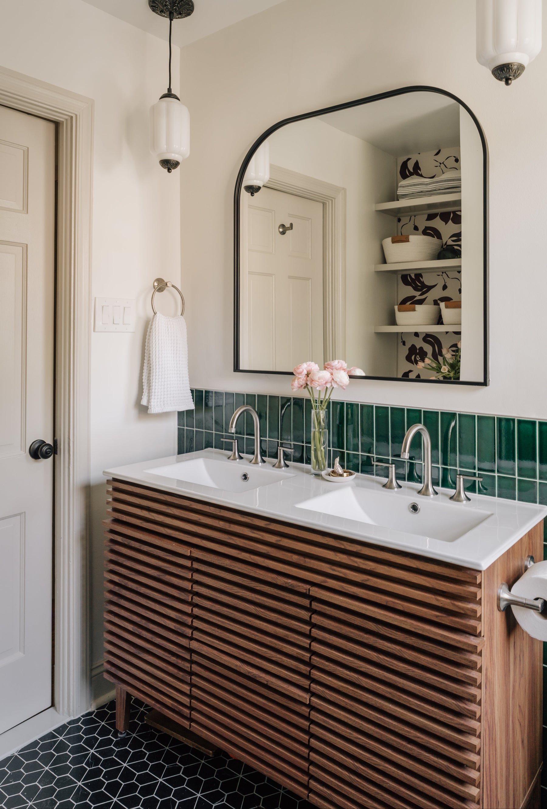 Bathroom with wooden vanity, white sinks, and emerald green tiled wall black and white pattern tile floor